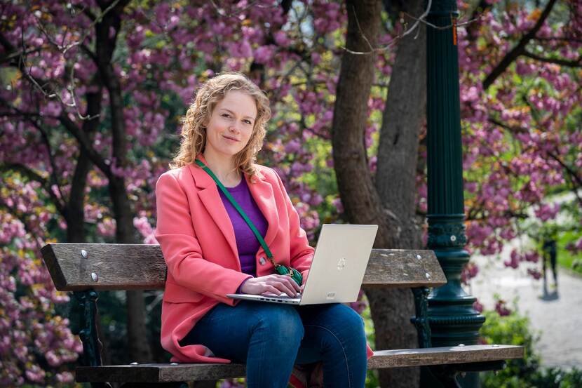 EU-medewerker Marije zit buiten op een bankje met haar laptop op schoot