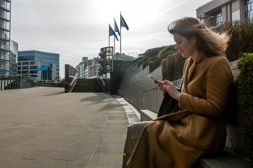 Charlotte Renckens met smartphone zittend op een bankje